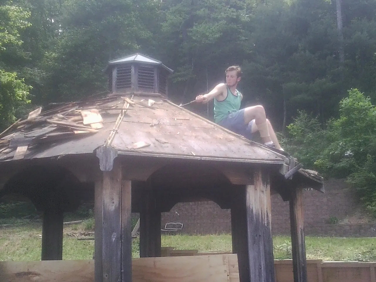 Tearing the old roof off a wooden gazebo before new shakes in Harvard