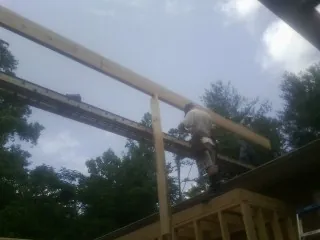 Carpenter setting a ridge beam over a new addition frame — Ice Dam Removal by Roofing Brothers in Harvard
